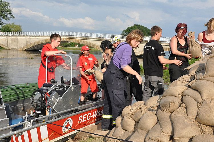 Starke Regenfälle führen im Juni 2013 Hochwasser der Elbe: Helfer der Wasserwacht sichern einen Flussdeich mit Sandsäcken, vermutlich in Sachsen-Anhalt oder Brandenburg