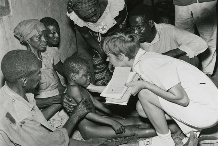 Krieg im nigerianischen Biafra: Einheimische und ausländische Rotkreuzhelfer behandeln ein Kind, dahinter die besorgten Angehörigen